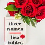A white book titled Three Women by Lisa Taddeo pictured with a bouquet of red roses