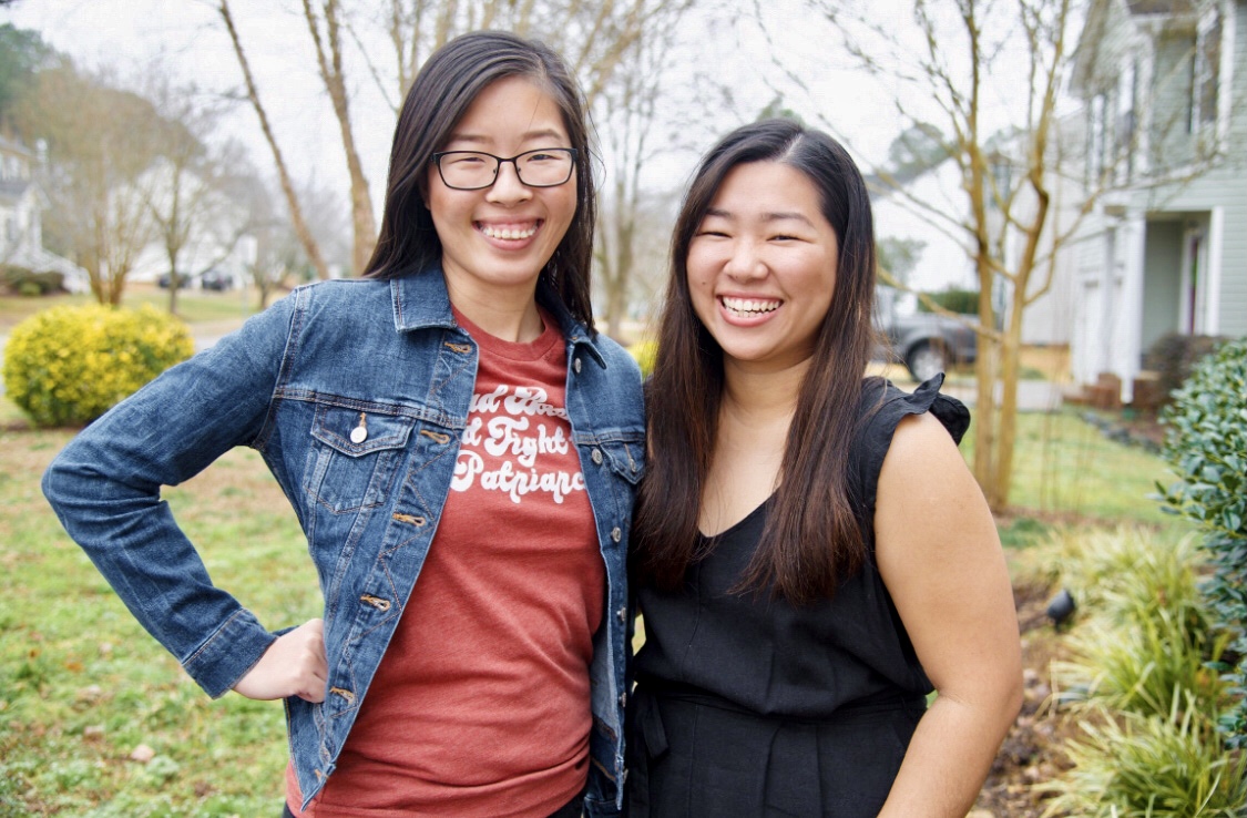 Two asian women with long hair are standing next to each other and smiling.
